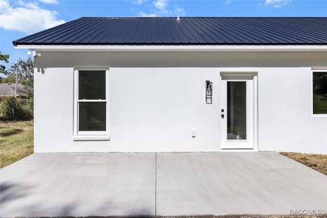 back of property with a patio area, metal roof, and stucco siding