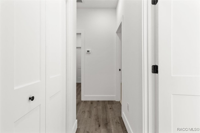 hall with baseboards, visible vents, and wood finished floors