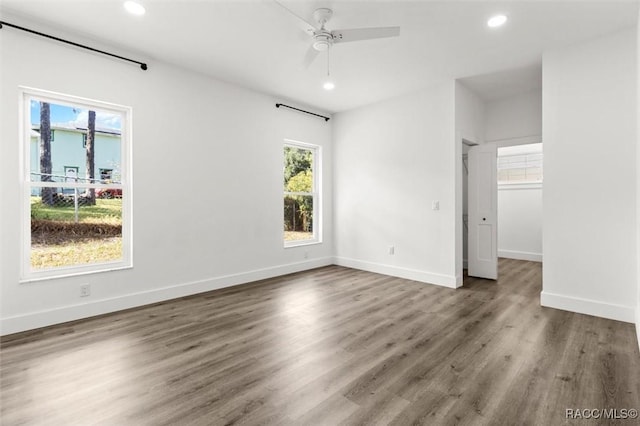 unfurnished bedroom with a walk in closet, recessed lighting, a ceiling fan, wood finished floors, and baseboards