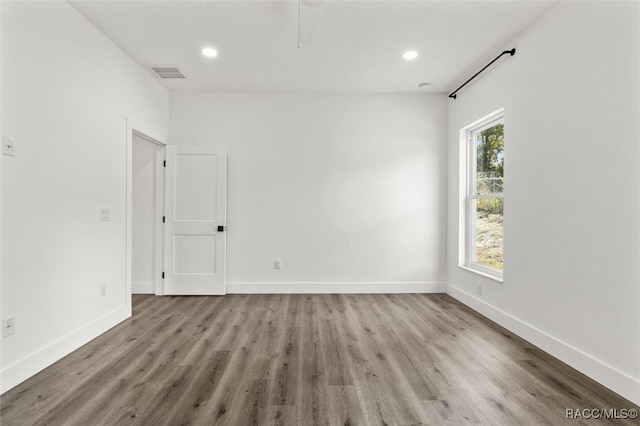 spare room featuring baseboards, wood finished floors, and recessed lighting