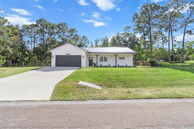 view of front of home with metal roof, an attached garage, concrete driveway, stucco siding, and a front lawn