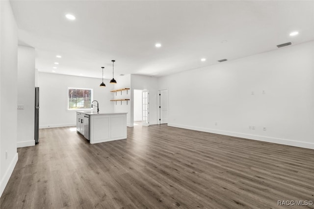 kitchen featuring freestanding refrigerator, visible vents, a sink, and wood finished floors