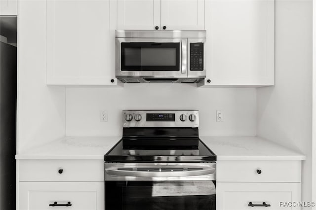 kitchen featuring appliances with stainless steel finishes, light stone countertops, and white cabinets