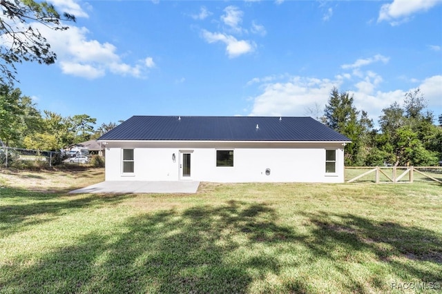 back of house featuring a lawn, a patio, metal roof, fence, and stucco siding