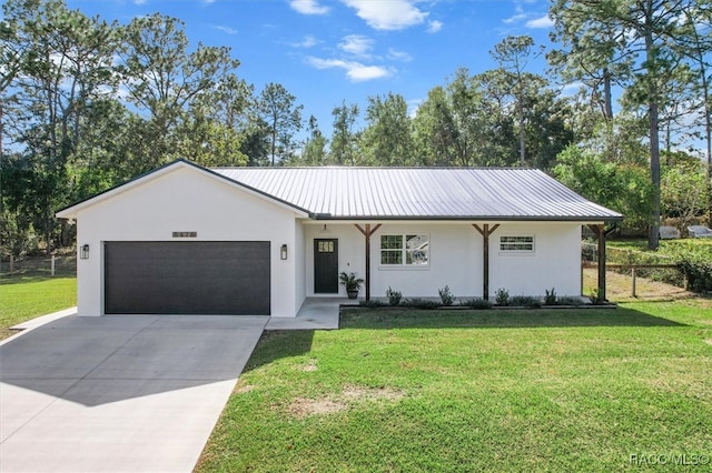 single story home with metal roof, a garage, concrete driveway, stucco siding, and a front lawn