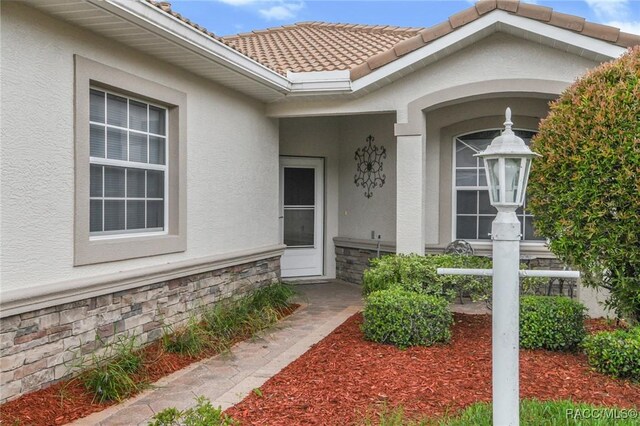916 W Skyview Crossing Dr, Hernando, FL 34442 - property entrance with stucco siding, stone siding, and a tiled roof