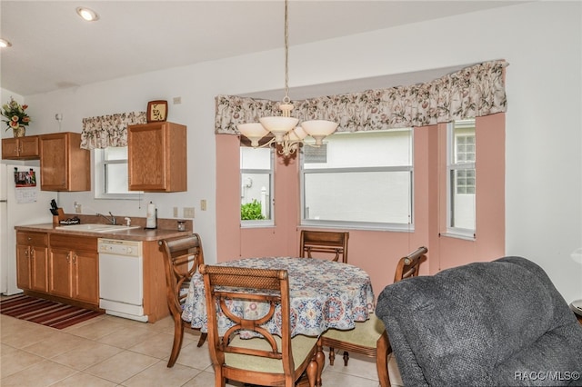 dining space with a healthy amount of sunlight, light tile patterned flooring, sink, and a chandelier