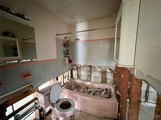 bathroom with tasteful backsplash, tiled shower / bath combo, and toilet