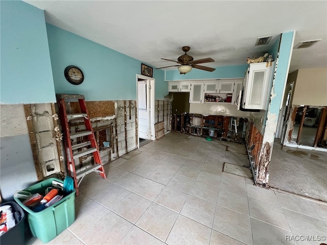 kitchen with ceiling fan, white cabinetry, and light tile patterned floors