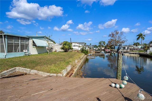 view of dock with a lawn and a water view