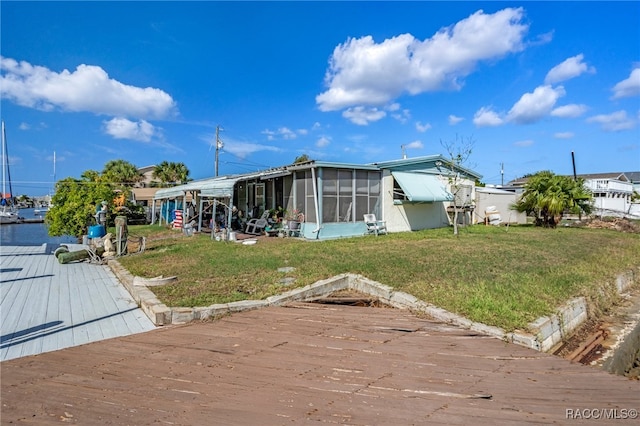 back of house featuring a sunroom and a lawn