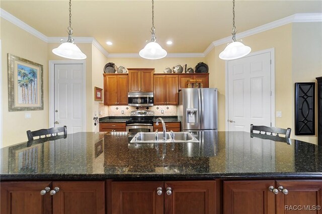 kitchen with stainless steel appliances, decorative light fixtures, sink, and a large island with sink