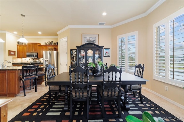 dining space with sink, crown molding, and light tile patterned floors