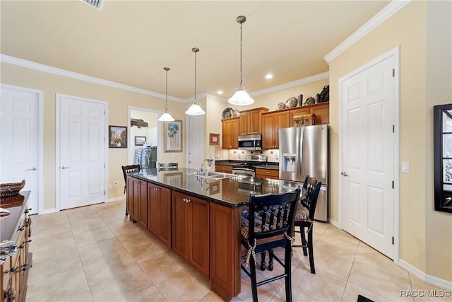 kitchen featuring a center island with sink, light tile patterned floors, pendant lighting, and appliances with stainless steel finishes