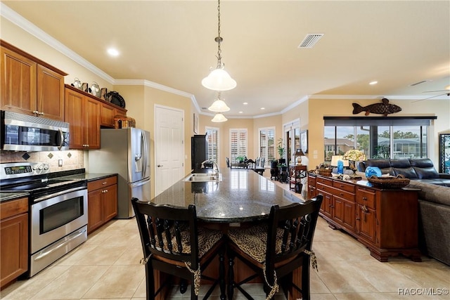 kitchen with sink, light tile patterned floors, a breakfast bar area, a kitchen island with sink, and appliances with stainless steel finishes