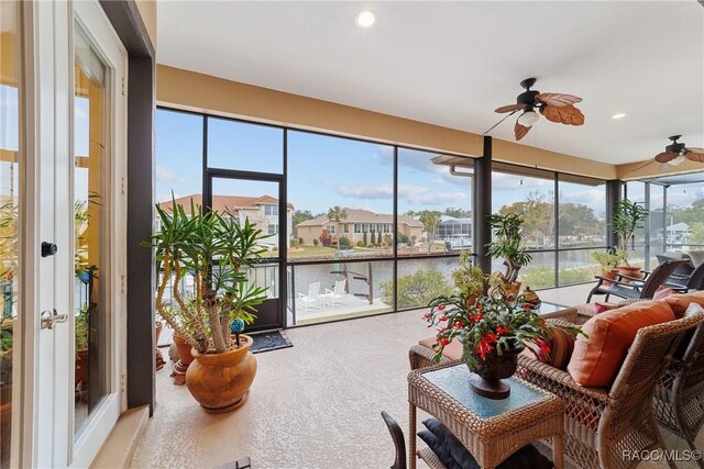 sunroom / solarium featuring ceiling fan, plenty of natural light, and a water view