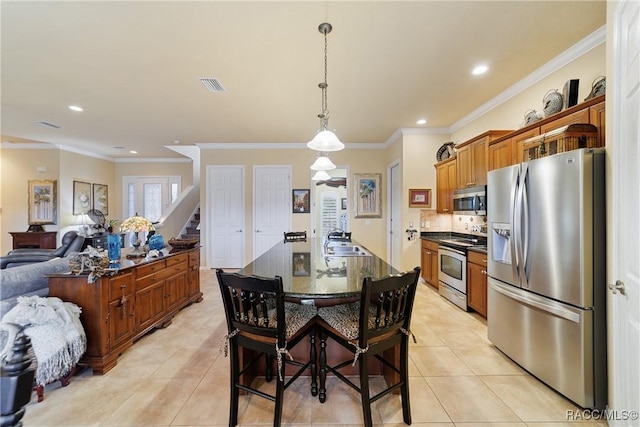 kitchen featuring sink, a breakfast bar area, a center island with sink, crown molding, and appliances with stainless steel finishes