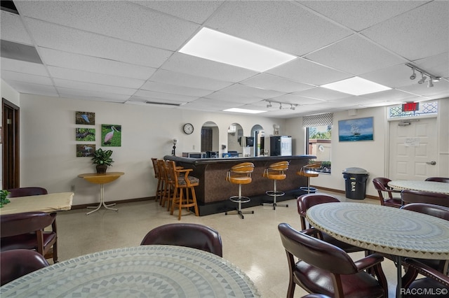 bar featuring a paneled ceiling, white fridge, and rail lighting