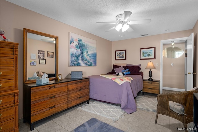 tiled bedroom with ceiling fan and a textured ceiling