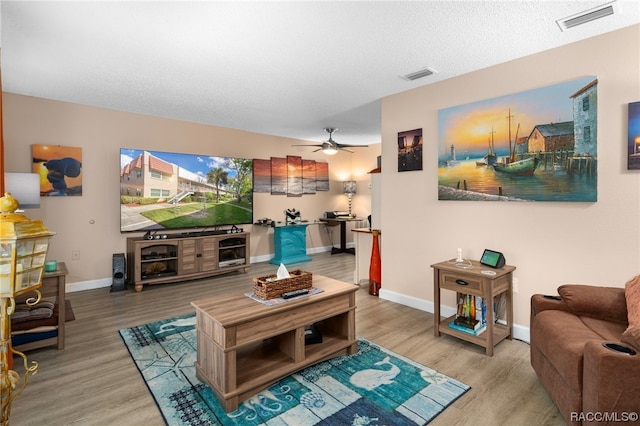 living room featuring ceiling fan, wood-type flooring, and a textured ceiling