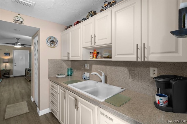 10038 62nd Ter N Unit 2, Saint Petersburg, FL 33708 - kitchen with a sink, tasteful backsplash, dark wood-type flooring, light countertops, and white cabinetry
