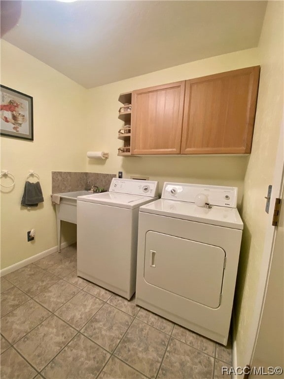 laundry area featuring cabinets, light tile patterned floors, and washer and clothes dryer