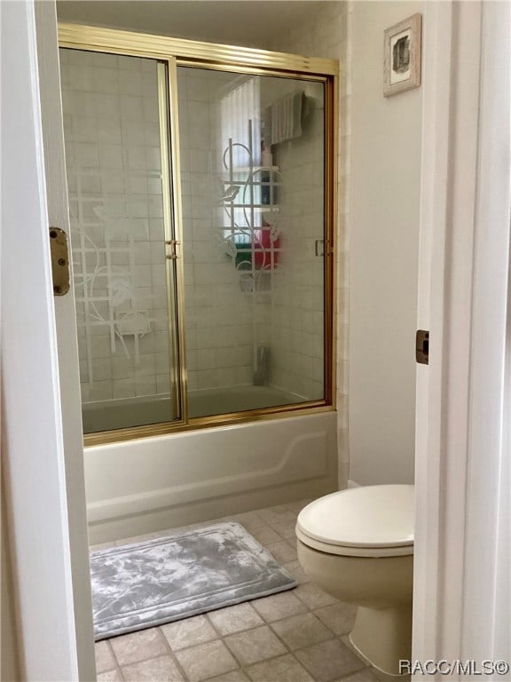 bathroom with tile patterned floors, enclosed tub / shower combo, and toilet