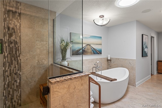 bathroom featuring tile patterned floors, tile walls, a textured ceiling, and shower with separate bathtub