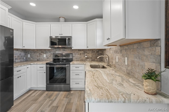 kitchen featuring light stone countertops, appliances with stainless steel finishes, sink, white cabinets, and light hardwood / wood-style floors