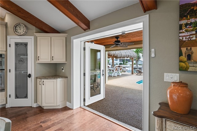 kitchen with vaulted ceiling with beams, ceiling fan, white cabinetry, and light wood-type flooring