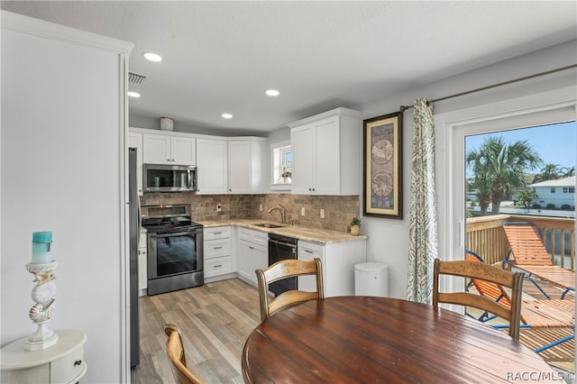 kitchen with decorative backsplash, stainless steel appliances, sink, light hardwood / wood-style floors, and white cabinetry