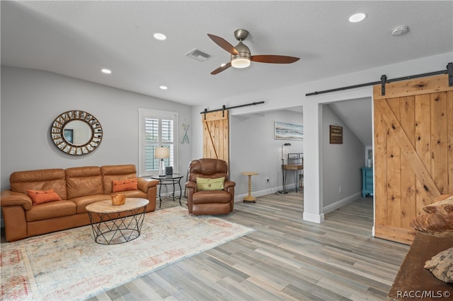 living room featuring a barn door, lofted ceiling, and light hardwood / wood-style flooring