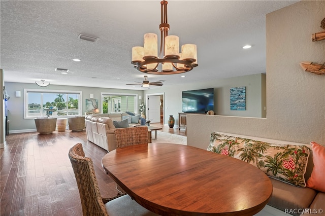 dining area featuring ceiling fan with notable chandelier, wood-type flooring, and a textured ceiling