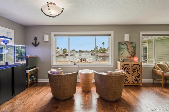 dining area featuring hardwood / wood-style floors, a water view, and a textured ceiling