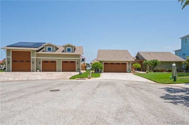 view of front of house featuring solar panels, a garage, and a front lawn