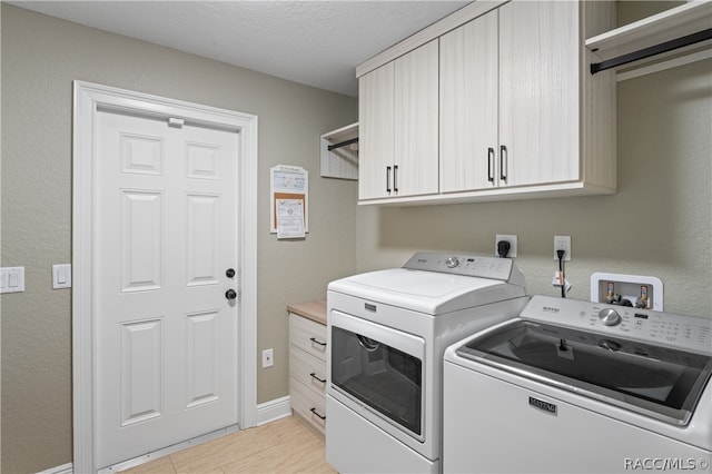 laundry room featuring washer and clothes dryer, cabinets, and a textured ceiling