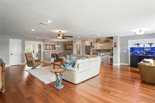 living room with french doors, a textured ceiling, light hardwood / wood-style floors, and ceiling fan