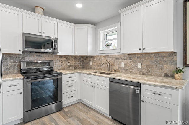 kitchen featuring white cabinets, light hardwood / wood-style floors, sink, and appliances with stainless steel finishes