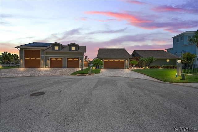 view of front of property with a lawn, solar panels, and a garage