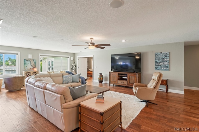 living room with ceiling fan, a textured ceiling, and hardwood / wood-style flooring