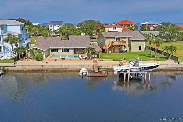 back of house featuring a lawn, a patio area, a water view, and a pool