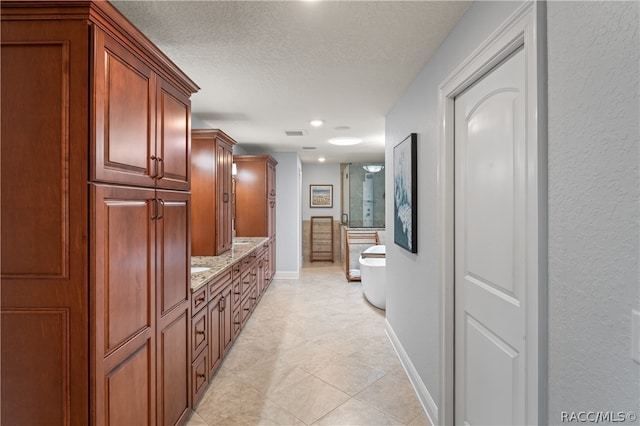 corridor with light tile patterned floors and a textured ceiling