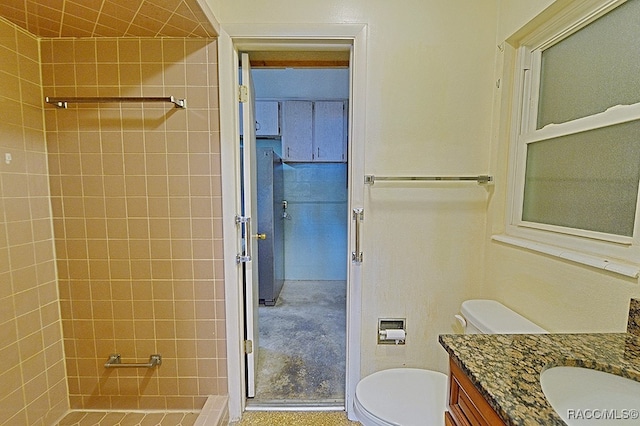 bathroom featuring vanity, toilet, and a tile shower