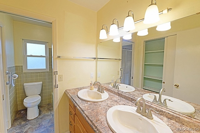 bathroom featuring vanity, toilet, and tile walls