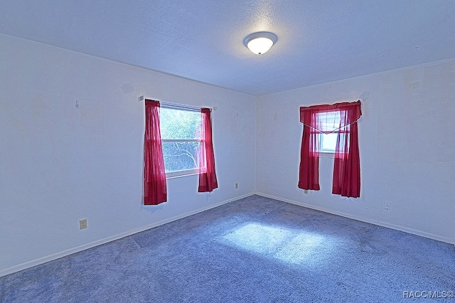 carpeted empty room featuring a textured ceiling