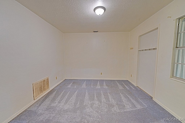 unfurnished room with carpet flooring and a textured ceiling