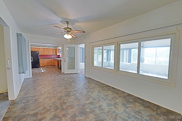 unfurnished living room with ceiling fan and a textured ceiling