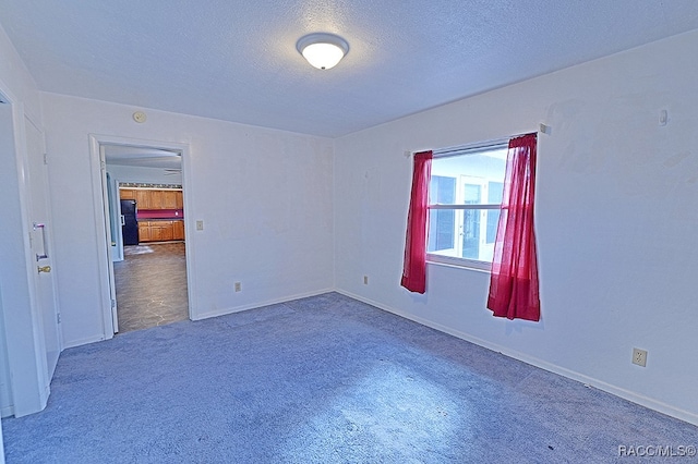 carpeted empty room featuring a textured ceiling