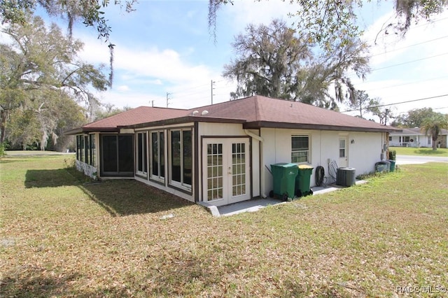 back of property with a sunroom, a lawn, central AC, and french doors