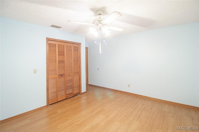 unfurnished bedroom with light wood finished floors, a textured ceiling, visible vents, and a closet